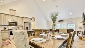 A spacious kitchen with modern appliances, a dining area with a wooden table set for four, and a cozy seating area with a fireplace. - Dream Ridge | Ellijay, GA (Ellijay)