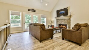 A living room with two sofas, a fireplace, and a TV mounted above it. - Dream Ridge | Ellijay, GA (Ellijay)