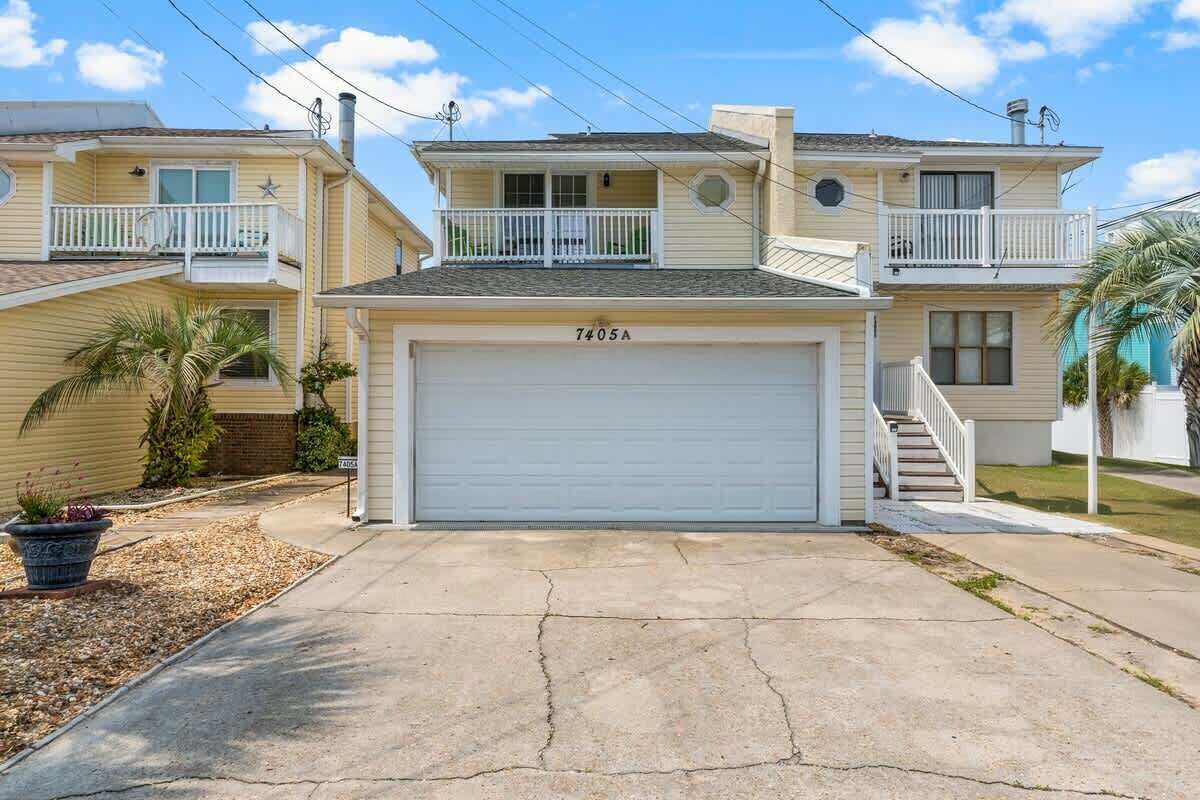 Ein zweistöckiges Haus mit Garage, Balkon und kleinem Vorgarten mit einer Palme.