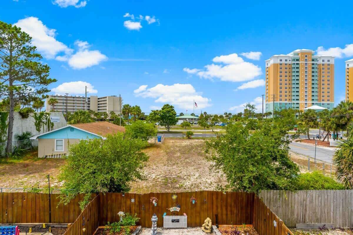 A residential area with a fenced yard, a small house, and a tall building in the background.