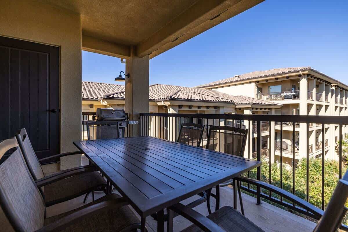 Ein Balkon mit Tisch und Stühlen, mit Blick auf ein Wohngebiet mit Gebäuden.