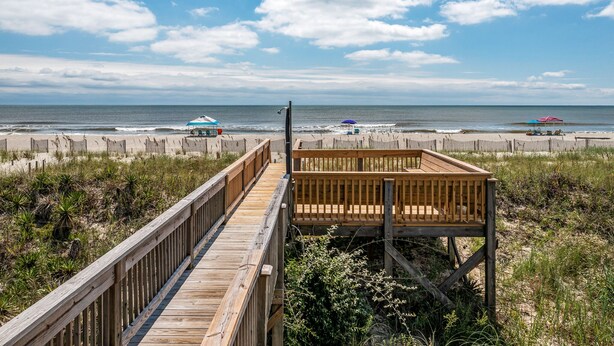 A wooden boardwalk leading to a beach with umbrellas and a wooden structure. - 'Pop's Inn" - Oceanfront Home, 4 Bedrooms / 2 Bathrooms (Holden Beach)