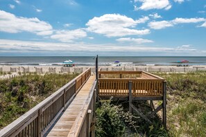 A wooden boardwalk leading to a beach with umbrellas and a wooden structure. - 'Pop's Inn" - Oceanfront Home, 4 Bedrooms / 2 Bathrooms (Holden Beach)