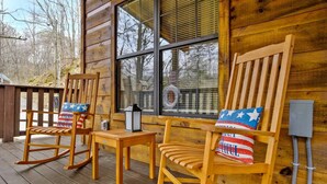 Two rocking chairs with American flag pillows on a wooden deck, a lantern, and a window with blinds. - Secluded Smokies Cabin | Private Pond + Hot Tub + King Bed (Sevierville)