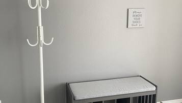 A room with a white coat rack, a grey bench, and a sign on the wall.