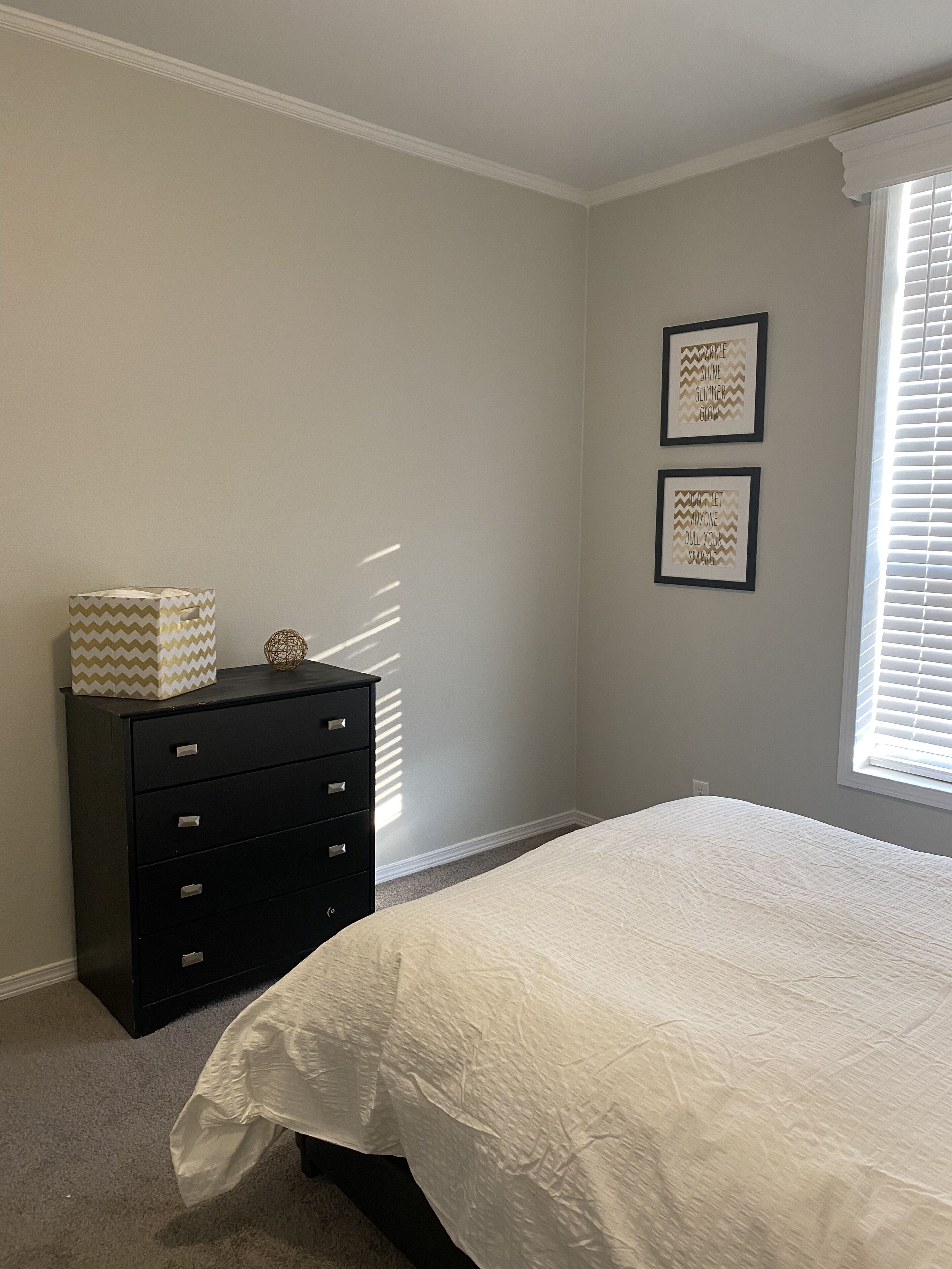 A bedroom with a bed, a dresser, and two motivational wall art pieces.