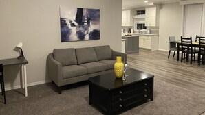 A modern living room with a grey sofa, a black coffee table with drawers, and a painting on the wall.