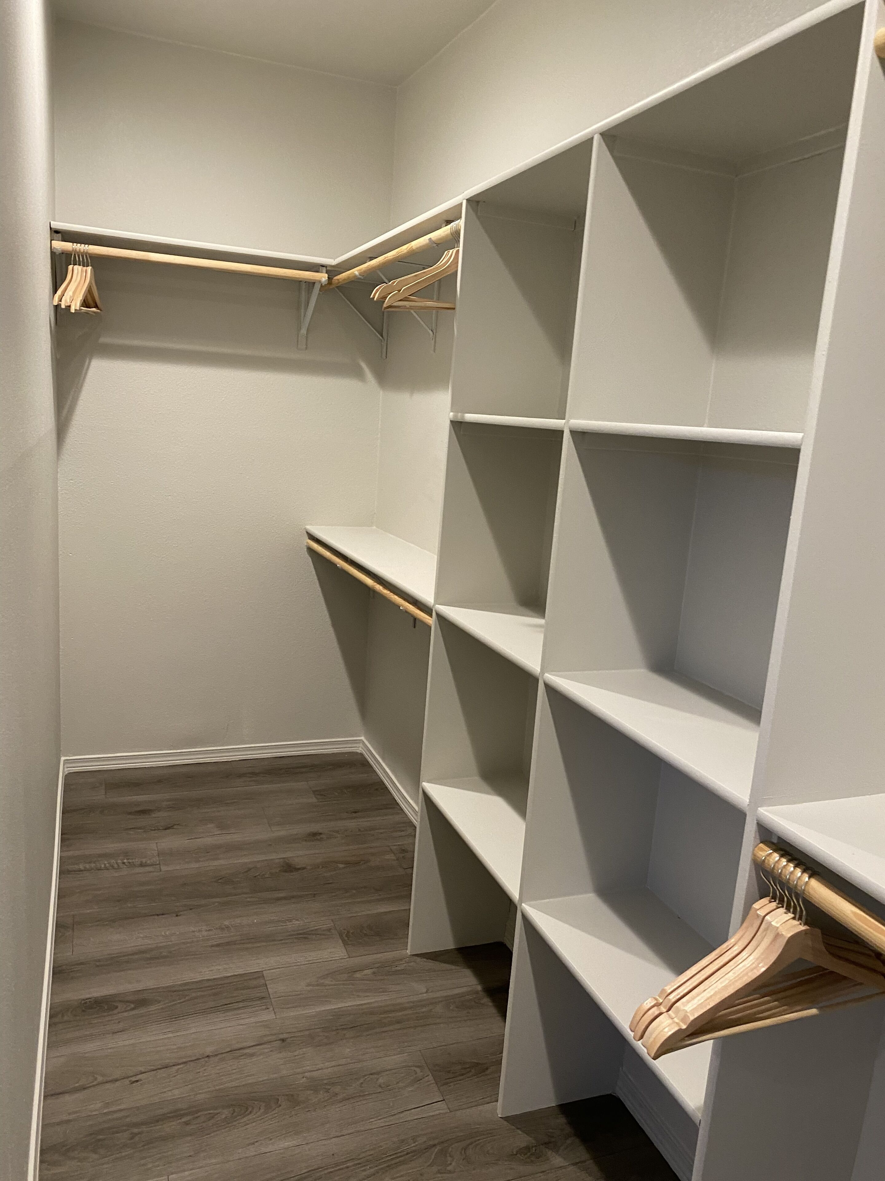 A walk-in closet with wooden shelves and a wooden floor.