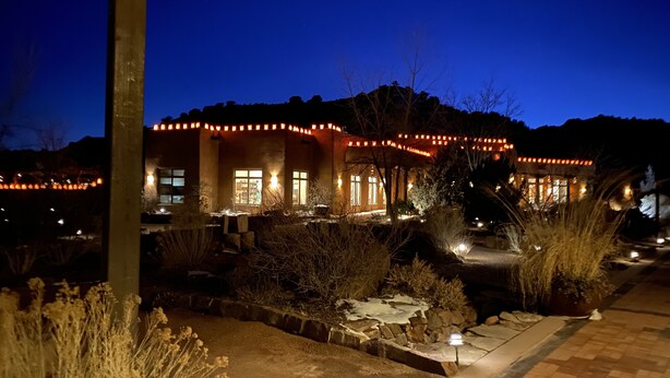 A building with a stone facade, multiple windows, and a well-lit entrance.