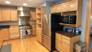 A modern kitchen with wooden cabinets, stainless steel appliances, and a built-in microwave shelf.