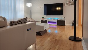 A modern living room with a sofa, a flat-screen TV, a floor lamp, and a coffee table.