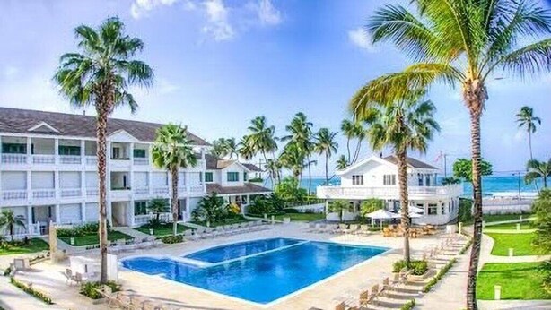 A resort with a large pool, palm trees, and beachfront views.