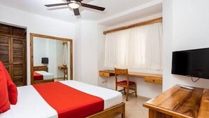 A bedroom with a bed, a desk, a chair, a television, and a ceiling fan.