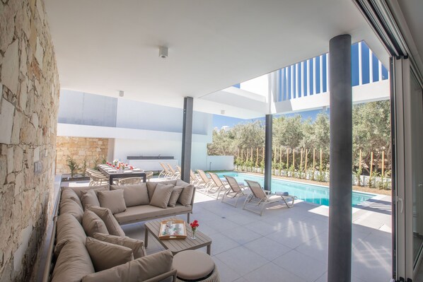 Relax by the pool in this inviting outdoor space, featuring a comfortable sofa, dining table, and lounge chairs.