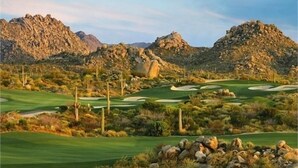 Un campo de golf en el desierto con terreno pedregoso y vegetación escasa.