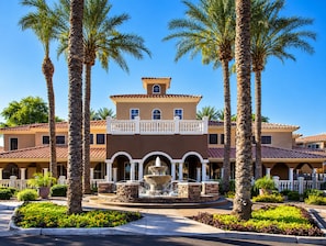 A two-story building with a central courtyard, surrounded by palm trees and a fountain.