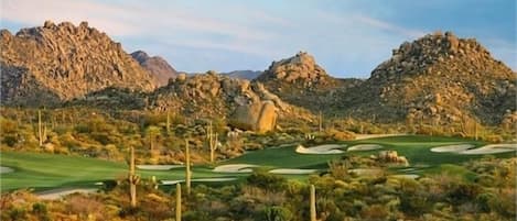 Un campo de golf en el desierto con terreno pedregoso y vegetación escasa.