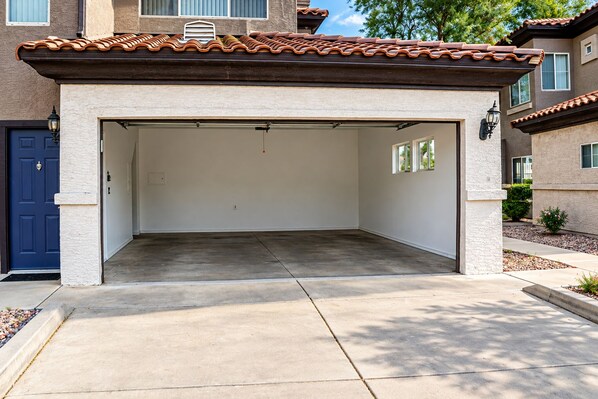A garage with a concrete floor, a blue door, and a textured wall. - 2 Bedroom / 2 Bath Condo at TPC Scottsdale (Scottsdale)