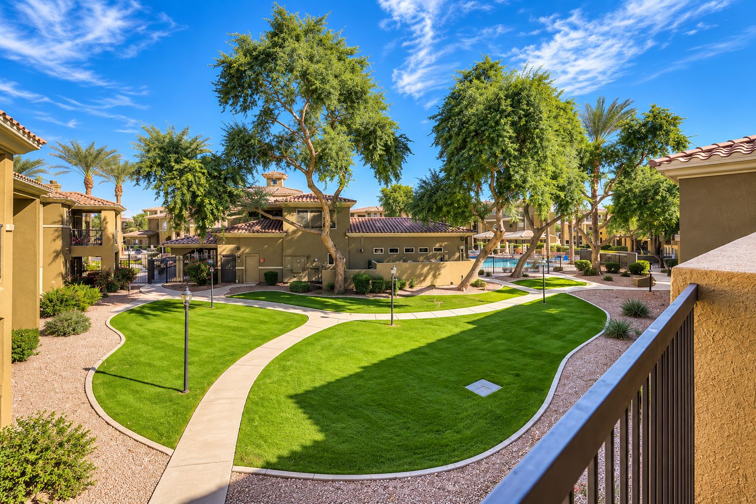 A residential area with a well-maintained lawn, a swimming pool, and multiple houses with balconies.