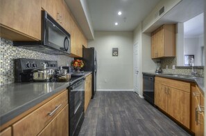 A modern kitchen with wooden cabinets, a stainless steel refrigerator, and a microwave.