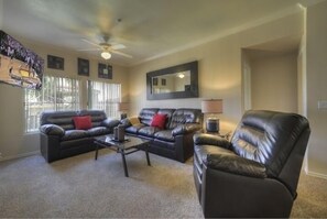 A living room with a black leather sofa, a coffee table, and a leather armchair.