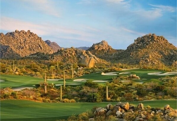 A desert golf course with rocky terrain and sparse vegetation.