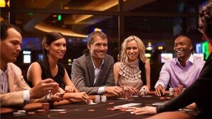 Eine Gruppe von Personen spielt an einem Casinotisch Karten, mit sichtbaren Chips und Karten.