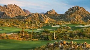 Ein Golfplatz in der Wüste mit felsigem Gelände und Kakteen.