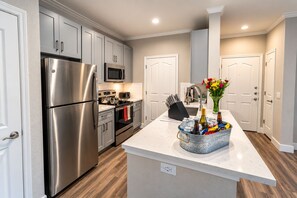 A modern kitchen with stainless steel appliances, a central island with a beverage cooler, and a microwave above the stove.