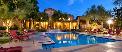 A swimming pool with lounge chairs and a building in the background.