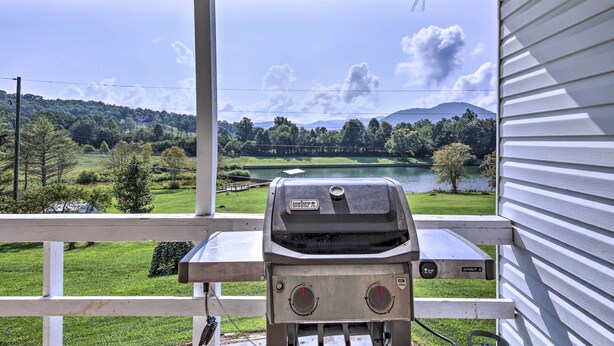 Una parrilla en un porche con vistas a un lago y colinas.