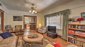 A living room with a sofa, armchair, coffee table, television, bookshelf, and a ceiling fan. - Lots of Parking & Only 2 Steps Into the Back Door! (Bisbee)