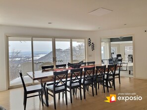 Ein Essbereich mit großem Tisch und Stühlen, großen Fenstern mit Blick auf eine verschneite Landschaft und einem modernen Interieur.