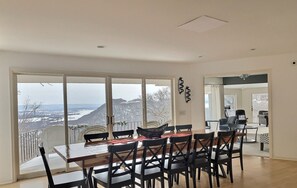 Ein Essbereich mit großem Tisch und Stühlen, großen Fenstern mit Blick auf eine verschneite Landschaft und einem modernen Interieur.