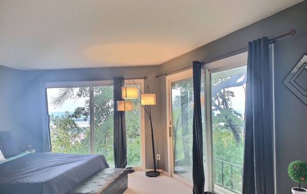 Ein modernes Schlafzimmer mit einem Bett, großen Fenstern und einer Stehlampe.