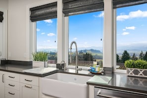 Una cocina con un amplio ventanal, un lavabo y un grifo.