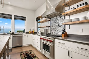 A modern kitchen with white cabinets, a stainless steel stove, and a patterned backsplash.