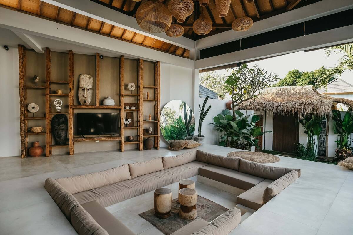 A modern living room with a large sectional sofa, wooden shelves with decorative items, and a large TV.