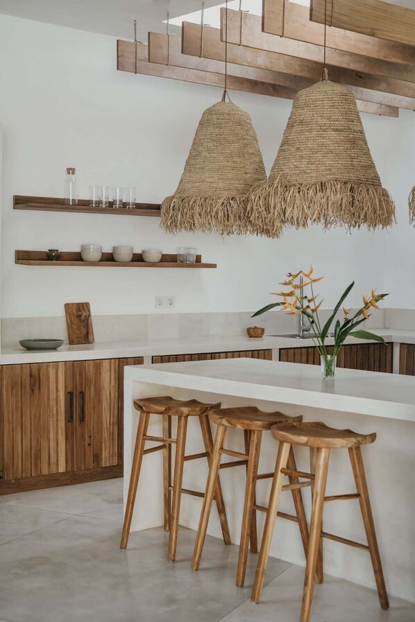 A modern kitchen with wooden cabinets, a white countertop, and a central island with bar stools.