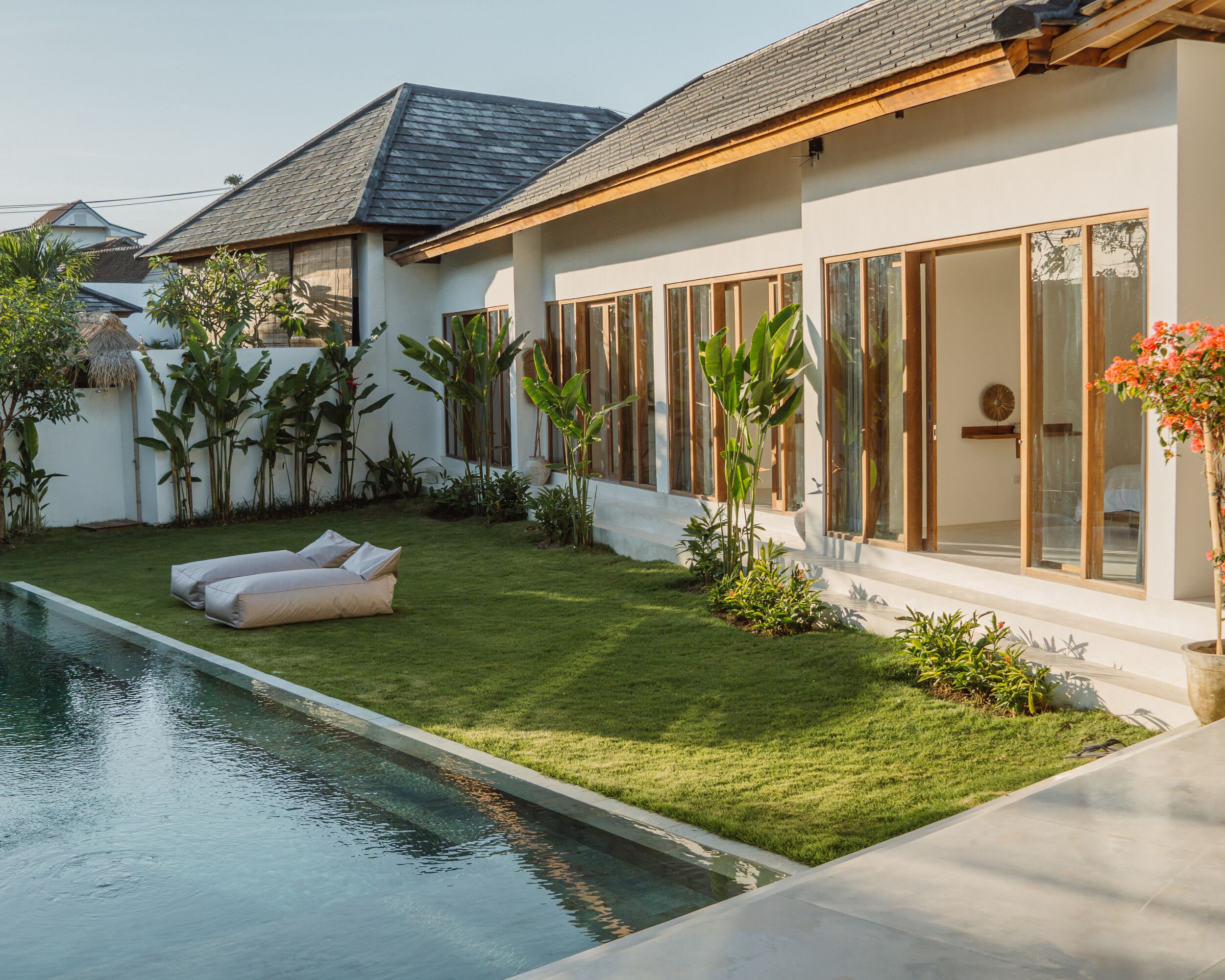 A modern house with a swimming pool, a well-maintained lawn, and large windows.