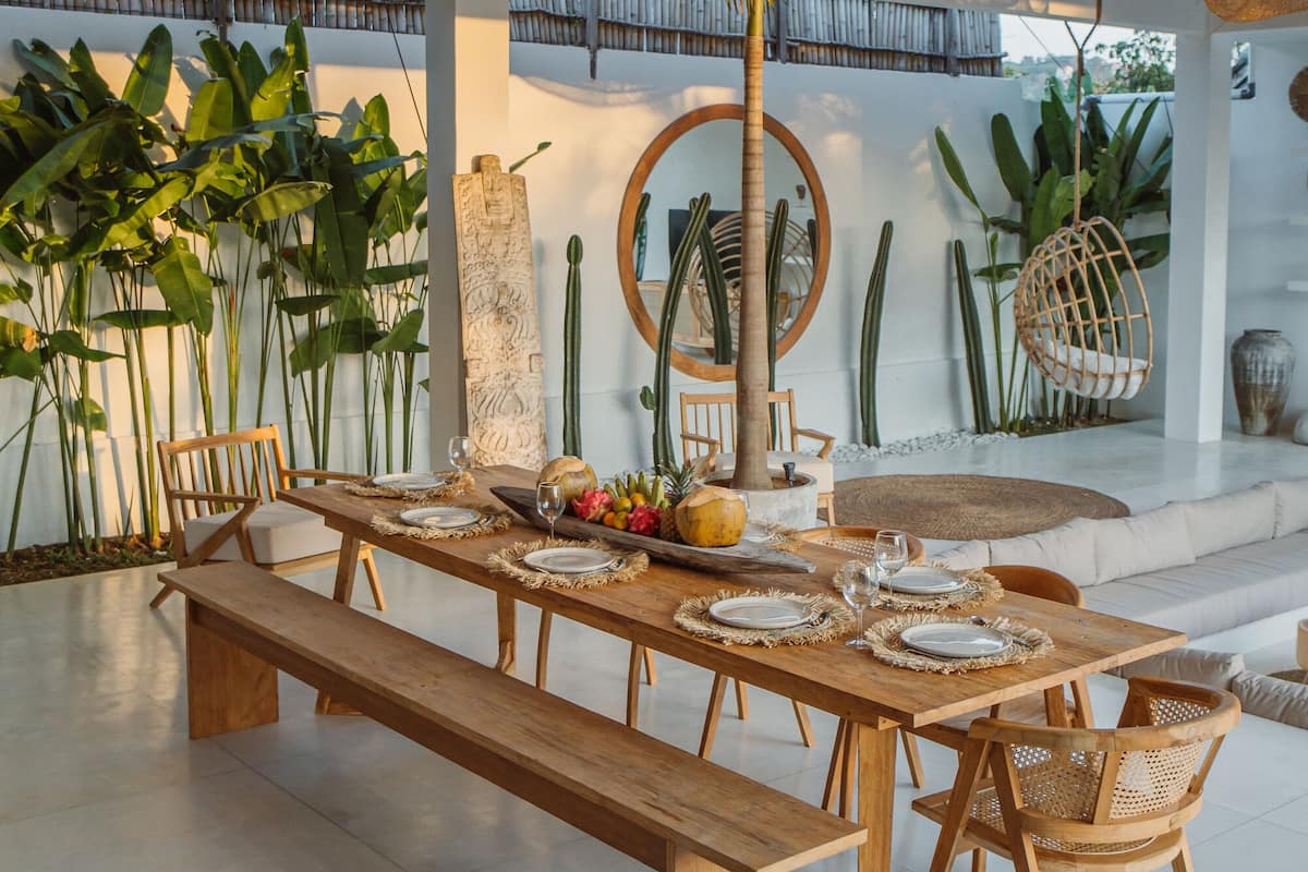 A spacious dining area with a long wooden table set for six, surrounded by wicker chairs.