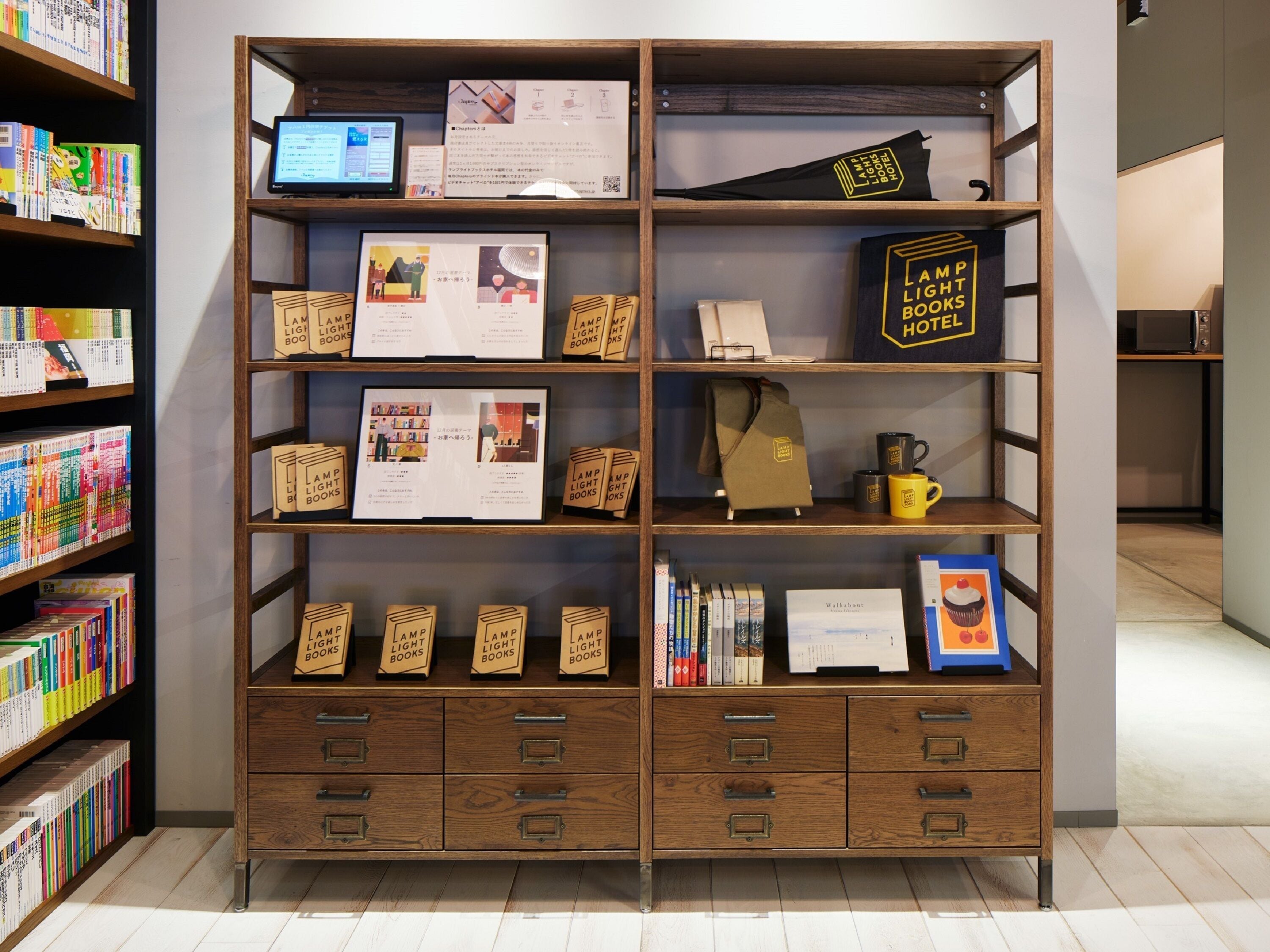 A wooden bookshelf with books, a laptop, and a sign reading "LAMP LIGHT BOOKS HOTEL".