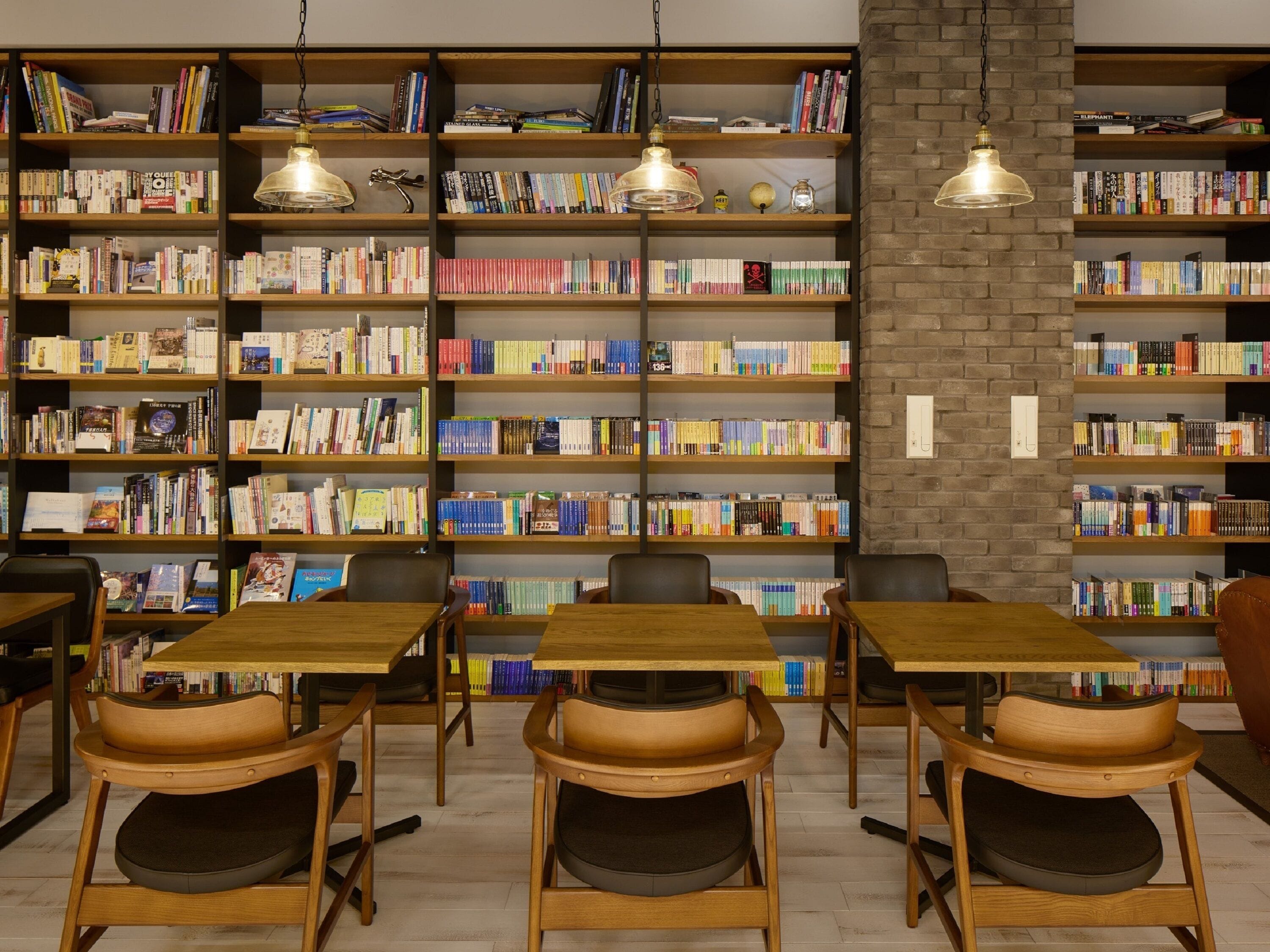 A library with multiple wooden bookshelves filled with books, wooden tables, and chairs.