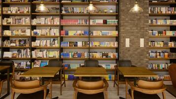 A library with multiple wooden bookshelves filled with books, wooden tables, and chairs.