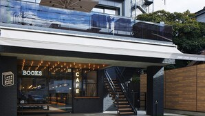 Un bâtiment moderne avec une façade en verre, un escalier apparent et une enseigne indiquant « LAMP LIGHT BOOKS HOTEL ».