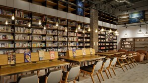 Une bibliothèque avec des tables et des chaises en bois, des étagères et des luminaires suspendus.