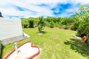 Un jardin arrière bien entretenu, avec une pelouse verdoyante, un chemin en briques et un petit espace potager.