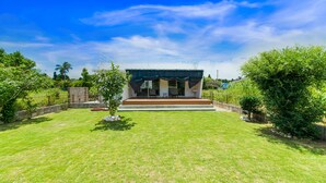 A modern house with a flat roof, a covered porch, and a well-maintained lawn.