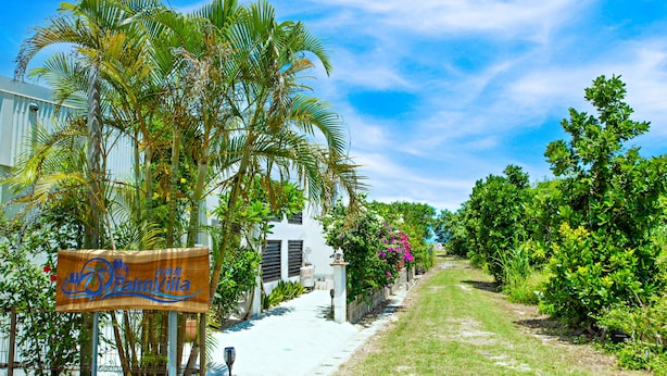 A pathway leading to a white building with a sign reading "Palm Villa."