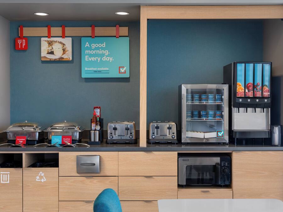 Espaço de café da manhã com máquina de café, torradeira e geladeira.